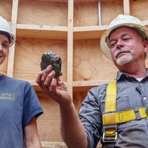 Site Supervisor Anna Shackelford and Director of Archaeology David Givens examine the burned wall fragment found in the Governor's Well.