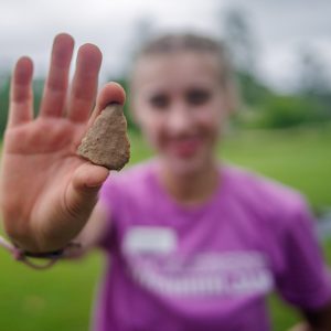 Field school student Natalie White holds a partial projectile point found in the cellar excavations.
