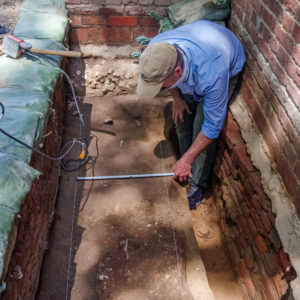 Archaeologist scanning a burial shaft with a handheld GPR unit