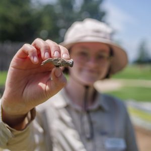 Field school student Julia Spencer holds a small hammer found at the cellar excavations.
