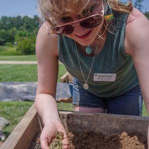 Field school student Rosie Latham holds green glass she found while screening soil from the cellar excavations.