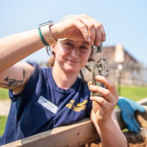 Staff Archaeologist Ren Willis holds a nearly complete glass bottle found at the cellar site.