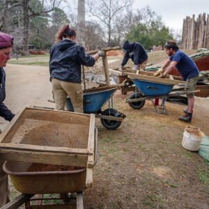 The team screens soil from the well excavations.