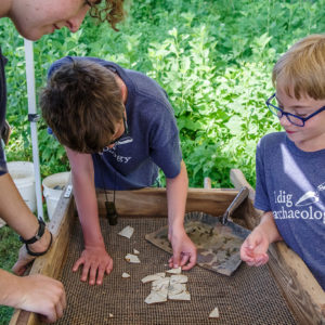 Campers piece together the whiteware plate found on the last day of Kids Camp as Archaeologist Brenna Fennessey looks on.