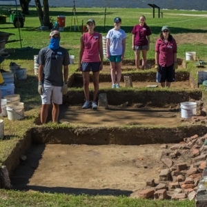 Students stand in excavation units