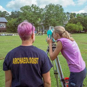 Staff Archaeologist Caitlin Delmas instructs field school student Natalie White in the use of surveying equipment.