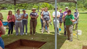 Field school student Sam Gallagher explains the week's excavations to other students and staff at the excavations outside the Dale House.