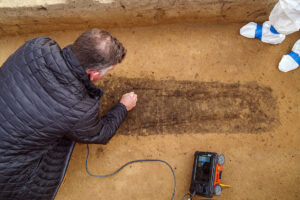 Director of Archaeology David Givens etches the location of a colonist's legs based on GPR surveys. GPR enables the team to have a very good idea of where human remains are so as to avoid damaging them during the excavations.