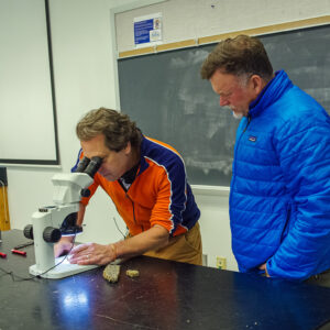 William & Mary geology professor Dr. Chuck Bailey examines a slice of rock found in the Governor's Well. Director of Archaeology David Givens looks on.