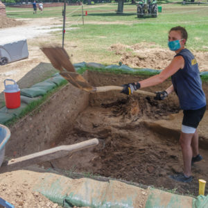 Archaeologist shoveling dirt into a wheelbarrow