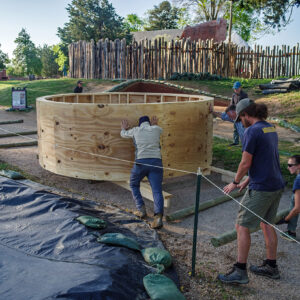 The archaeological team moves the well ring up the gravel path to the archaeology shed.