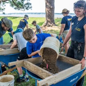 Archaeological Field Technician Eleanor Robb supervises a camper as he screens for artifacts.