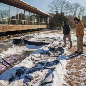 Archaeological Field Technicians Josh Barber and Hannah Barch inspect the condition of the covered Archaearium excavations after a snowstorm.