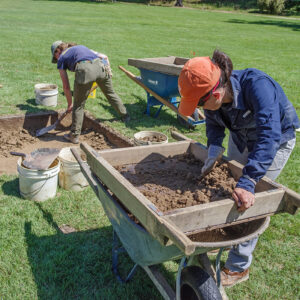 Senior Staff Archaeologist Mary Anna Hartley screens for artifacts in soil excavated by Archaeological Field Technician Ren Willis.