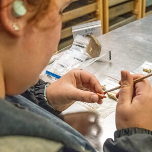 Archaeological Field Technician Hannah Barch labels and bags artifacts in the lab. She applies Paraloid B-72 as a base for a label on a sherd of ceramic. B-72 is a reversible adhesive so the label can be removed if necessary.