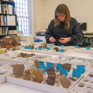 Senior Curator Leah Stricker looks for potential mends in our crucible collection. Examples of partially mended crucibles are in the foreground.