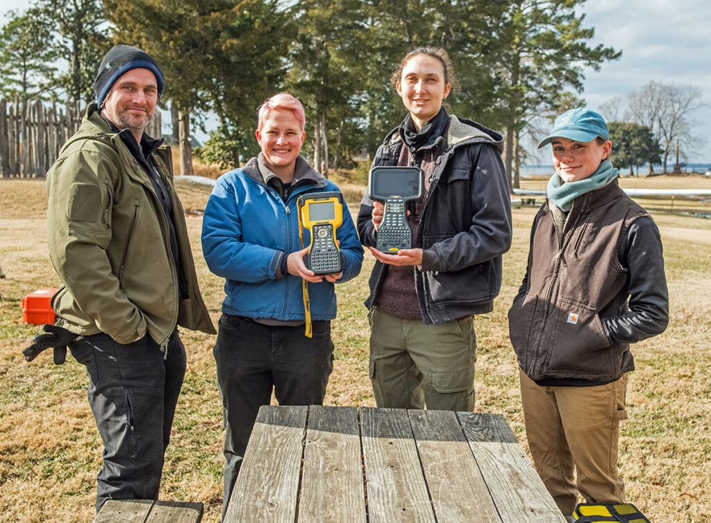 Staff Archaeologist Gabriel Brown, Staff Archaeologist Caitlin Delmas (holding the old surveying controller), Senior Staff Archaeologist Anna Shackelford (holding the new surveying controller), and Staff Archaeologist Natalie Reid