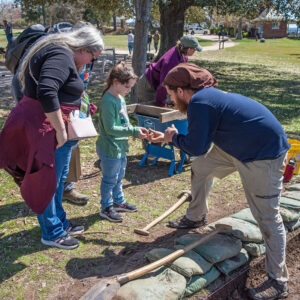 Archaeological Field Technician Josh Barber shares a sherd of ceramic he found with a young visitor.