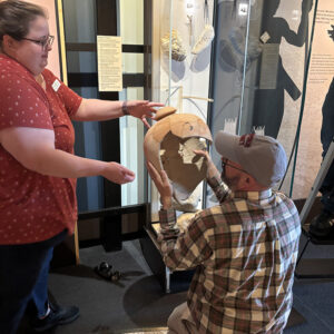 Curatorial Assistant Lauren Stephens and Director of Collections and Conservation Michael Lavin remove the olive jar from the Archaearium to mend the newly found sherd.