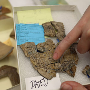 Curator Leah Stricker points out a dragon motif on a Bartmann jug medallion