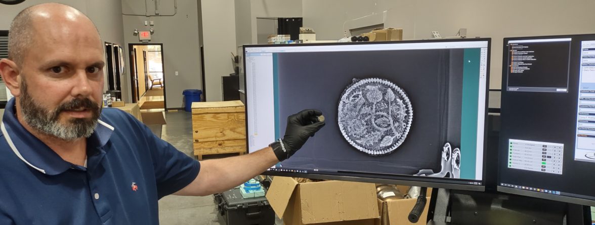 Director of Collections & Conservation Michael Lavin holds a rusted King's Touch Token next to an X-ray of the object.