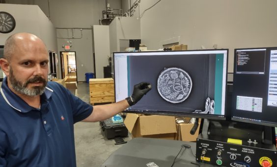 Director of Collections & Conservation Michael Lavin holds a rusted King's Touch Token next to an X-ray of the object.