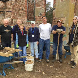 Volunteer group photo in front of house ruins