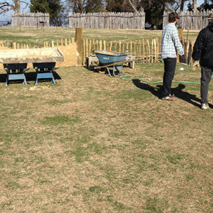 Two staff members examine in-progress reconstructed low church wall