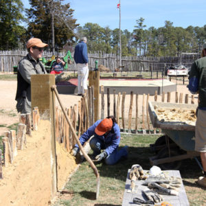 a man watches two people working on the church walls