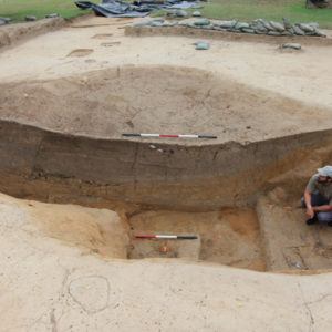 Archaeologists measuring stratigraphic layers in an excavation unit wall