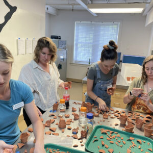 Curator Leah Stricker guides the Field School students through mending flower pots found near the Church Tower.