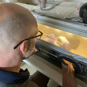 Field School student Kurt Fredrickson using the air abrasion machine to remove corrosion from a spike from Fort Pocahontas' gun platform.