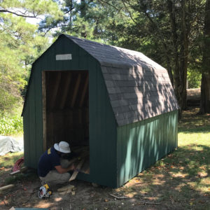 Archaeologist measuring wood pieces next to the entrance of a shed