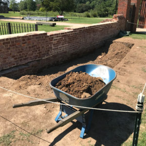 Wheelbarrow filled with dirt sitting by the edge of an excavation unit