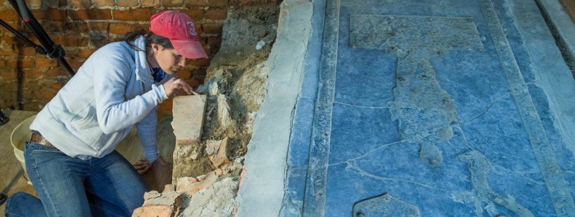 Archaeologist excavates under granite tombstone