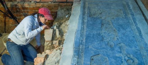 Archaeologist excavates under granite tombstone