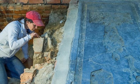 Archaeologist excavates under granite tombstone