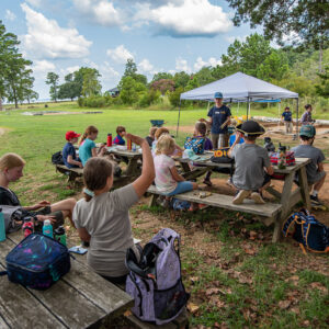 Staff Archaeologist Natalie Reid and the campers discuss the archaeology journals the kids used to record their activities and findings.