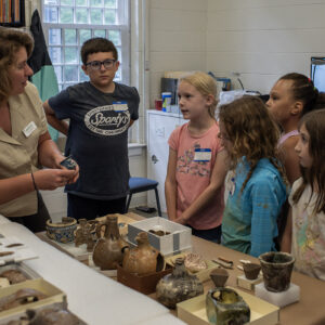 Curator Leah Stricker teaches Kids Camp attendees about some of the artifacts in the collection.