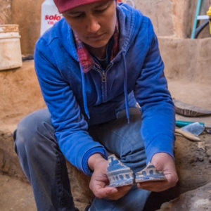 Archaeologist holding two parts of a ceramic vessel