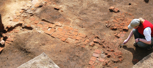 archaeologist troweling next to a brick chimney base