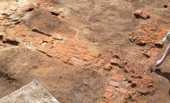 archaeologist troweling next to a brick chimney base