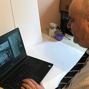 Seated man in a suit looking at a presentation on a computer screen