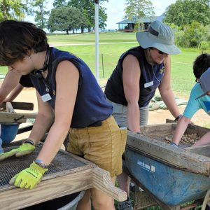 Archaeologists and campers screening for artifacts