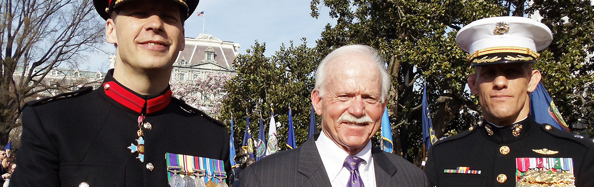 Man in a suit standing between two uniformed guards