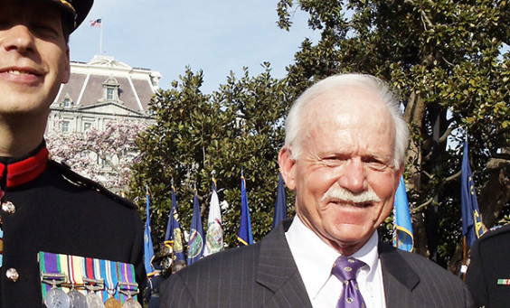 Man in a suit standing between two uniformed guards