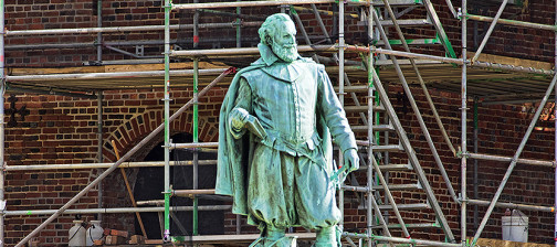 John Smith statue and a brick church tower surrounded by a scaffold in the background