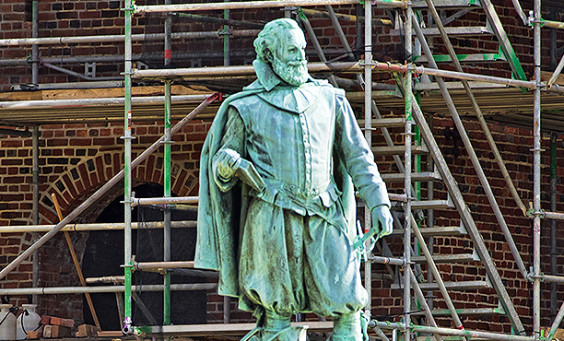 John Smith statue and a brick church tower surrounded by a scaffold in the background