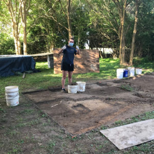 Archaeologists excavating in front of trees