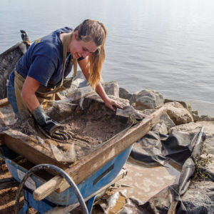 archaeologist water screening next to a river